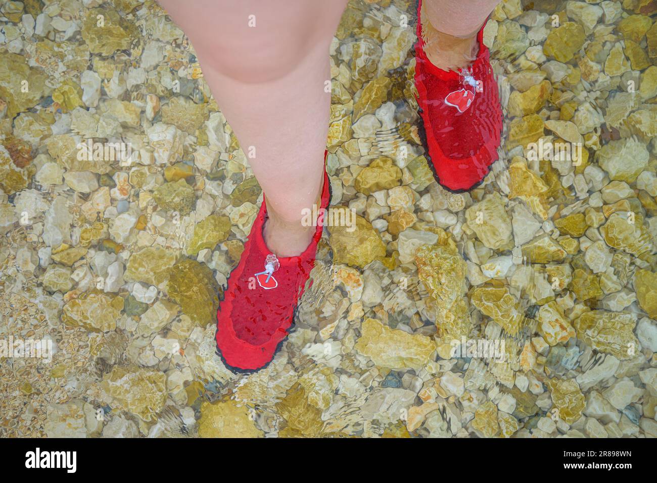 Legs in aquashoes on a rocky bottom. Stock Photo