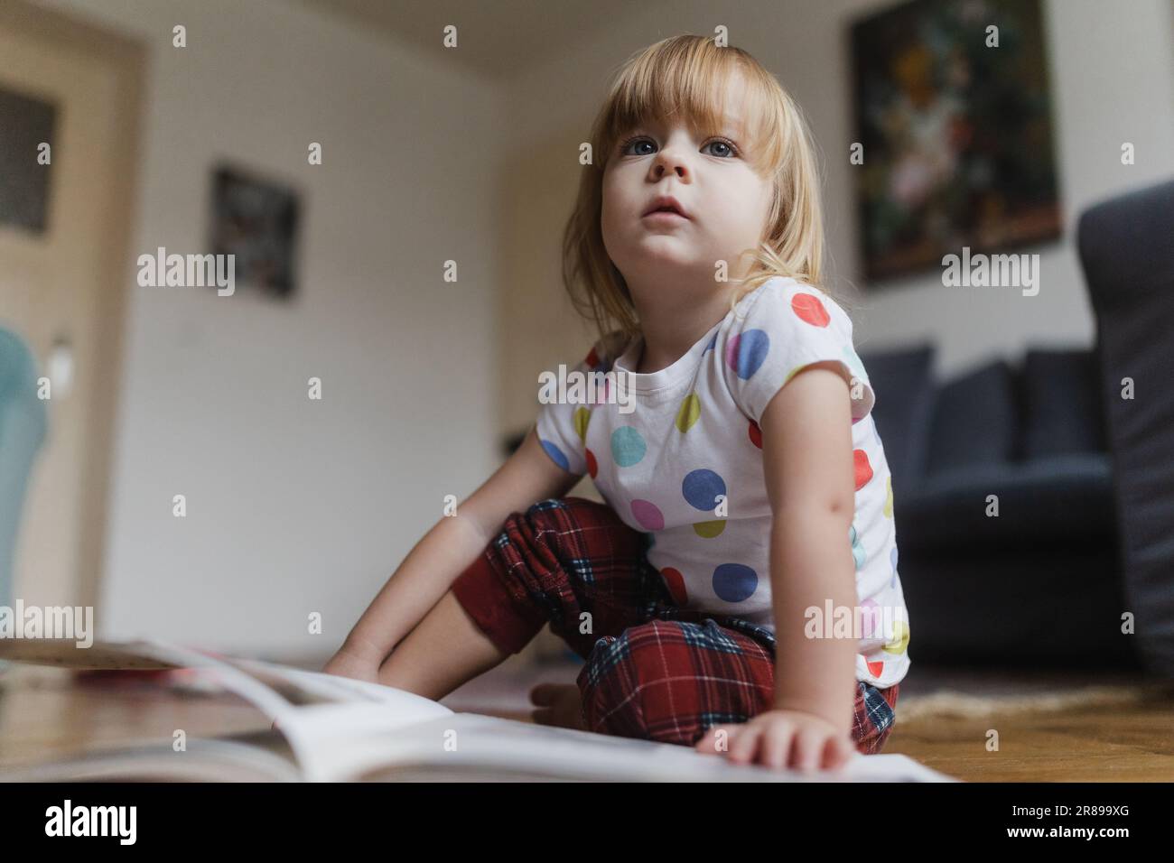Cute little girl reading book sitting on the floor Stock Photo - Alamy