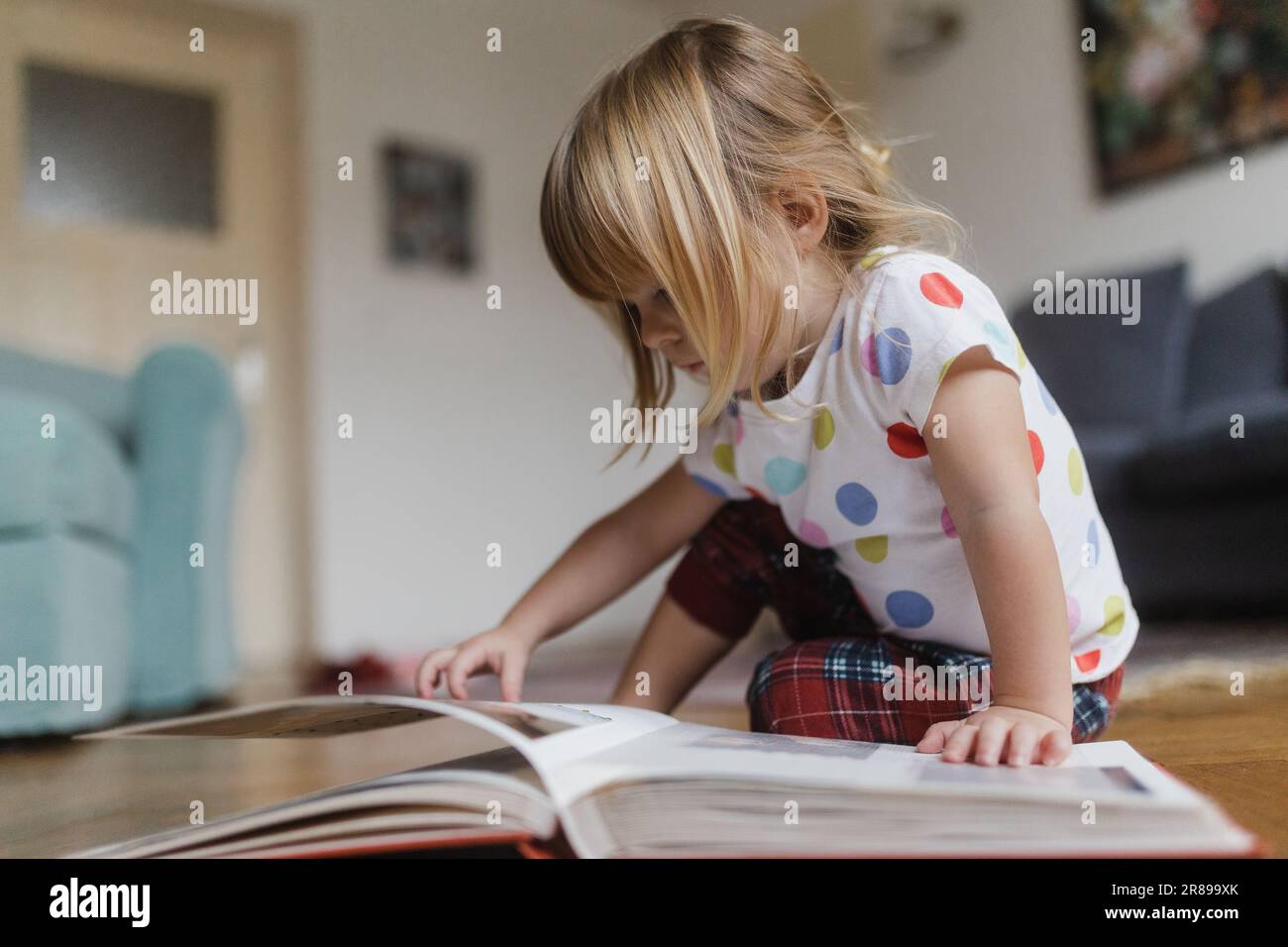 Cute little girl reading book sitting on the floor Stock Photo - Alamy