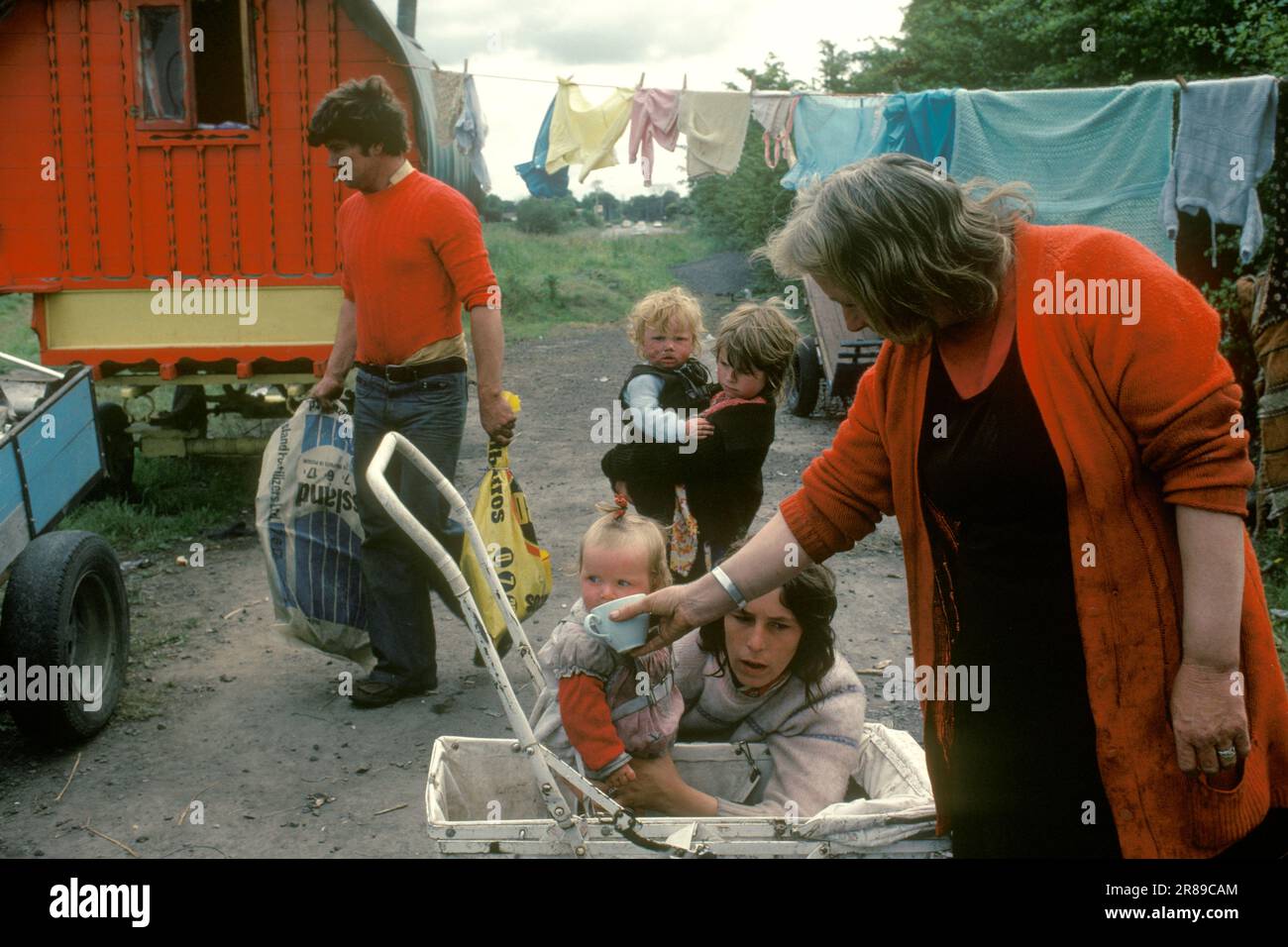 Irish travellers family, grandmother, mother, father, children pitched at the side of the road. The red wagon is a traditional wooden Bow Topped horse drawn wagon. 1979 1970s HOMER SYKES Stock Photo