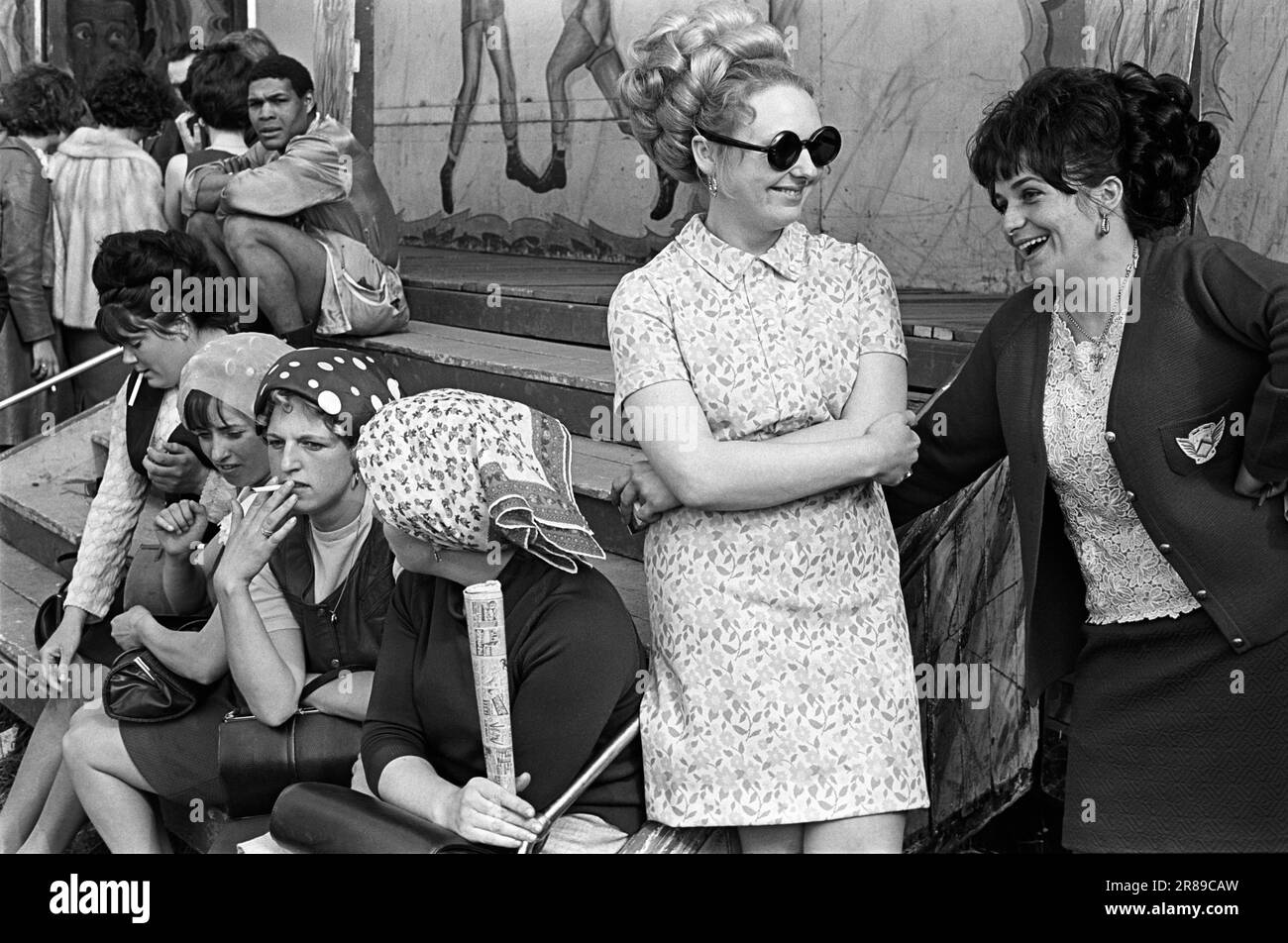 Gypsy women outside Pat McKeowen's prize fighting fairground boxing booth. Three women are wearing headscarfs to hid their hair that's in curlers. The woman in dark glasses wears her hair in a 'beehive', fashionable at the time. The Derby, an annual festival of horse racing.  Epsom Downs, Surrey England June 1969 1960s UK HOMER SYKES Stock Photo