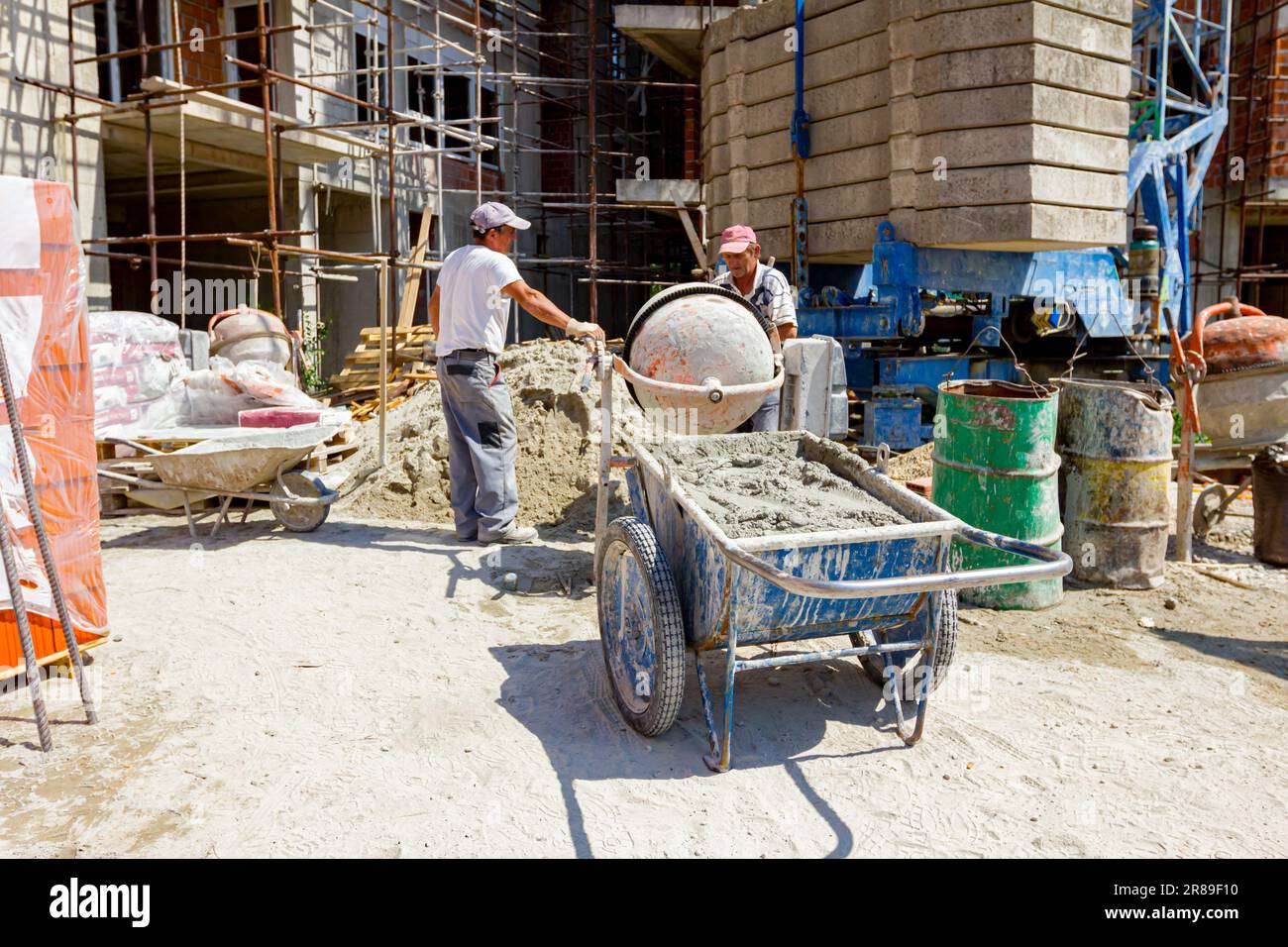Full wheelbarrow with unloaded fresh mortar from cement mixer machine