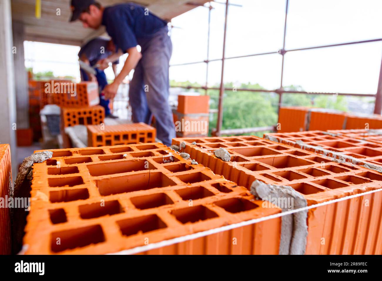 Bricklaying wall with red blocks and mortar, tighten rope placed for