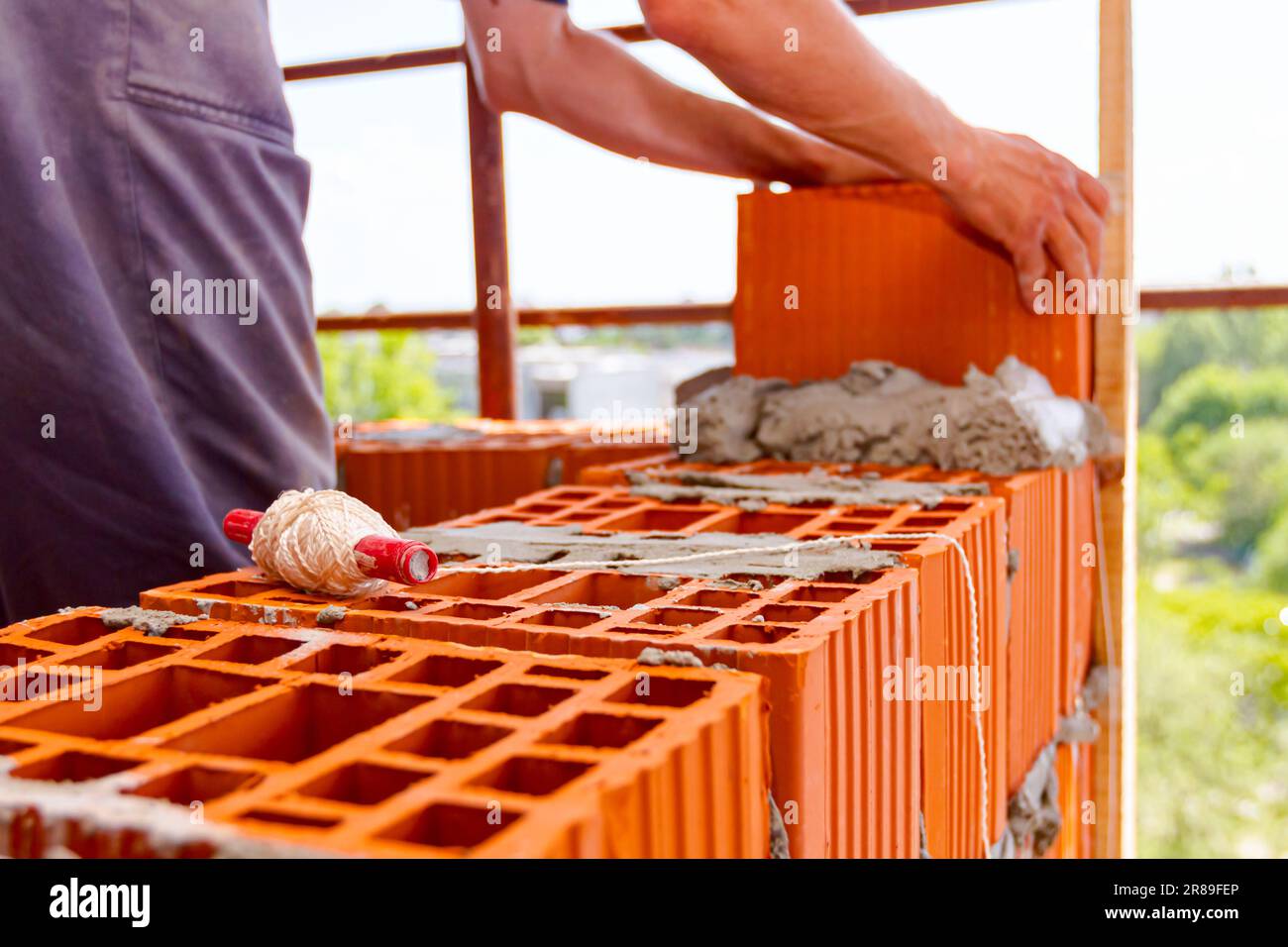 Spool of construction string line placed in red blocks. Tool to help worker  for set straight distances on new edifice, in background mason uses red bl  Stock Photo - Alamy