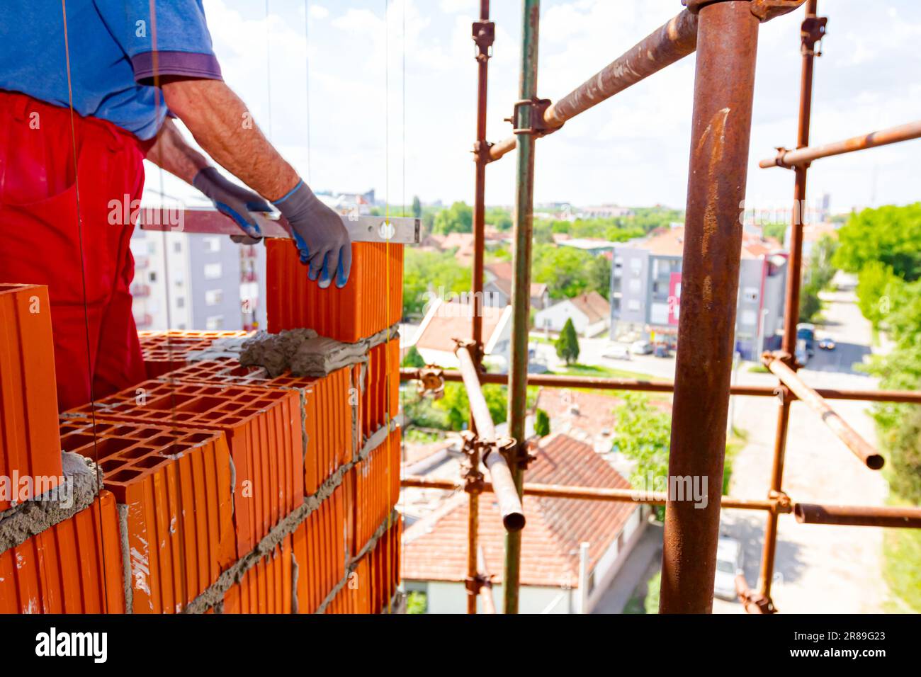 Builder is using a spirit level to check new red brick wall made of red ...
