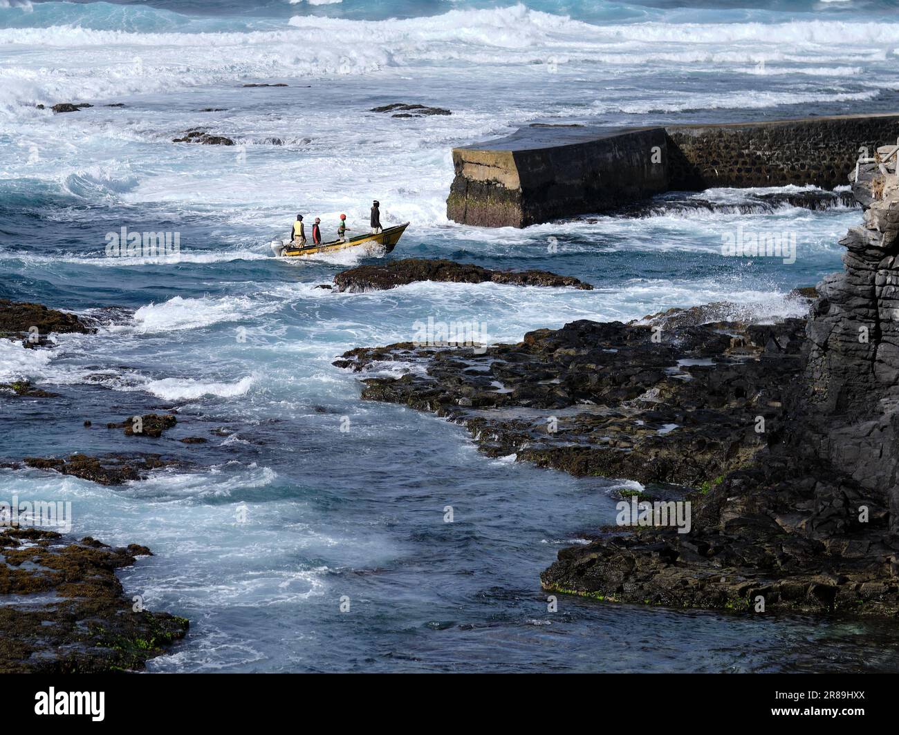 Small fishing boat returning to a difficult harbour entrance in Ponta do Sol, Santo Antao Cabo Verde Stock Photo