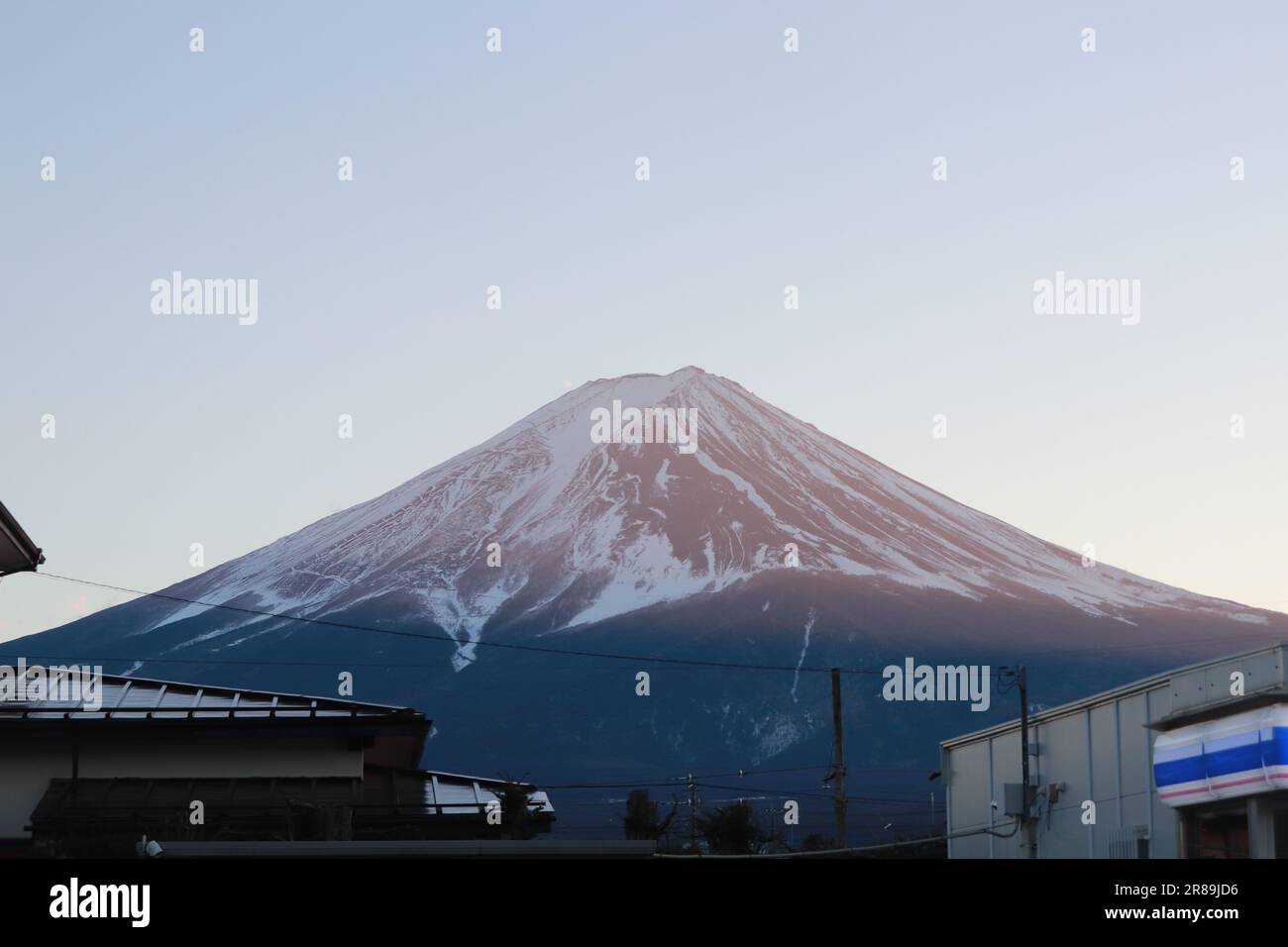 An areal view of the Fuji mountain rising above a skyline of buildings in the background Stock Photo