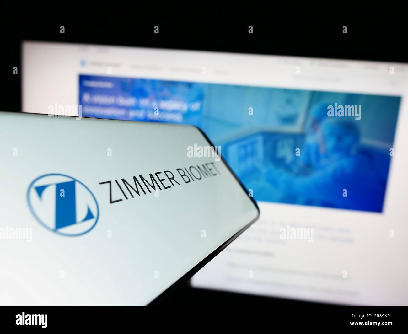 Smartphone with logo of American company Zimmer Biomet Holdings Inc. on screen in front of website. Focus on center-right of phone display. Stock Photo