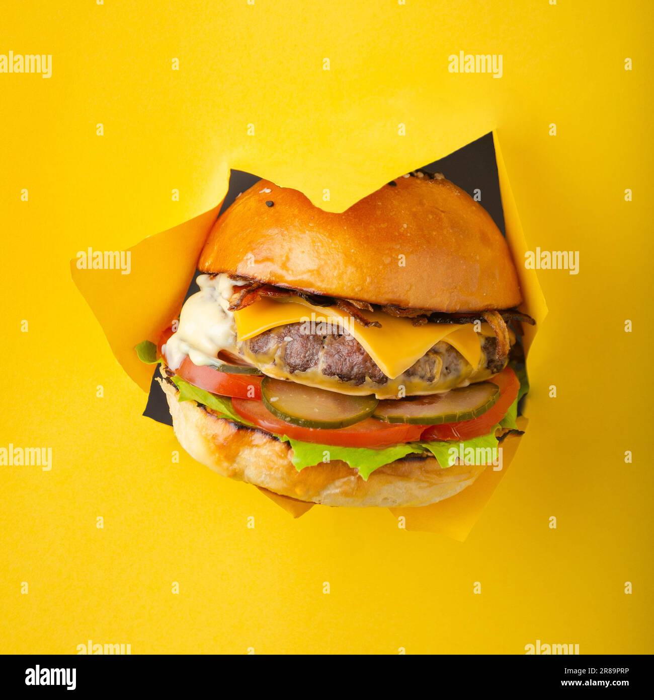 Delicious cheeseburger coming out of yellow colored background Stock Photo