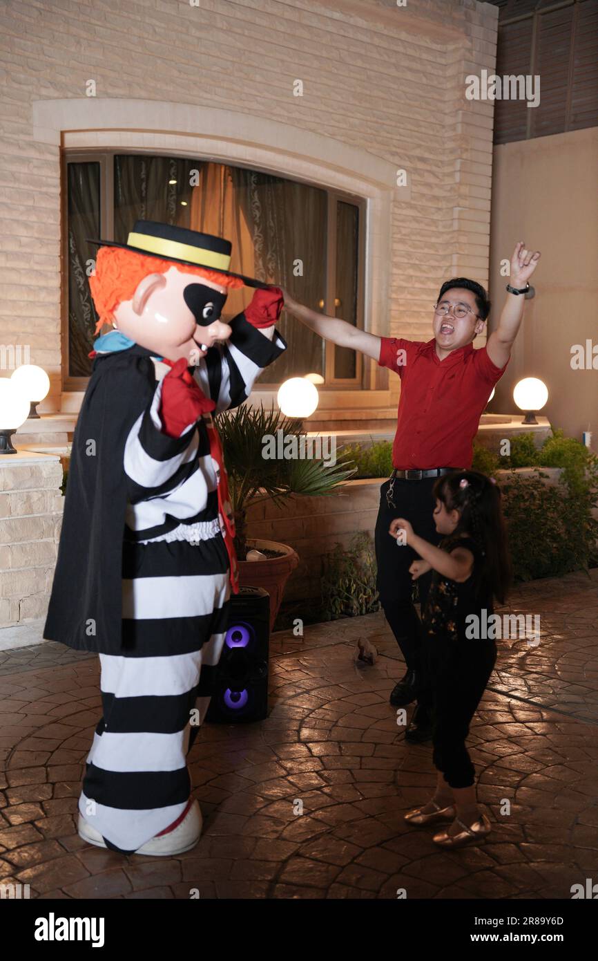 A little child is dancing with Mcdonalds' character 'The Hamburglar' kids' party at night. Stock Photo