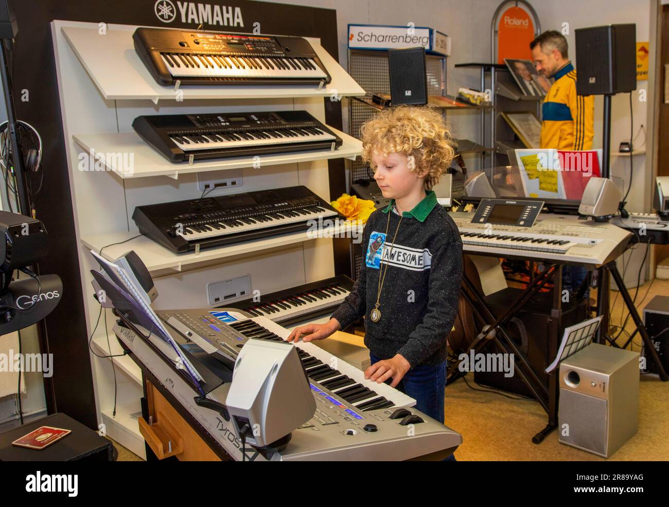 Netherlands, boy is trying a keyboard in a music shop before he and his father are making a decision for a brand and type to buy. Stock Photo