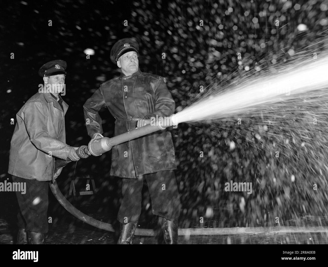 Current 21-5-1950: The fire brigade prepares for winterHenki Kolstad and Inger-Marie Andersen have the lead roles in the film 'Vi gifter oss', which is filmed in Oslo. To make it look like winter, even though the filming takes place in the autumn, the fire brigade has sprayed soap foam in the streets.  A mixture of water and liquid soap is whipped into foam in this comet jet tube, and in a few seconds fire constable Larsen and fire foreman Jacobsen have created the softest Christmas atmosphere out of a gray autumn street.  Photo: Sverre A. Børretzen / Aktuell / NTB ***PHOTO NOT IMAGE PROCESSED Stock Photo