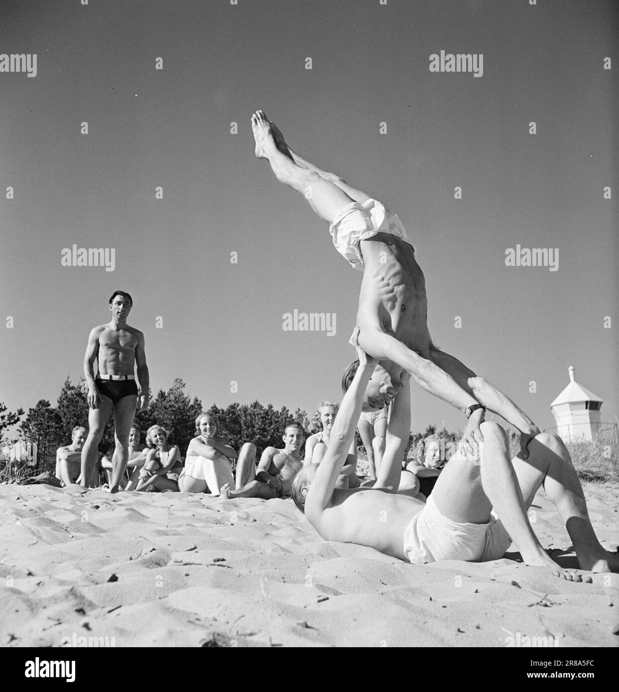 Current 15-1949: Sun and summer over Mandal- A lying Ross Farestad together with Ernst Thomassem gives a display of gymnastics for admirers in the background. The small round house t.h. is the 'Grandmother Lighthouse'.  Photo; Sverre A. Børretzen / Aktuell / NTB  ***PHOTO NOT IMAGE PROCESSED*** Stock Photo