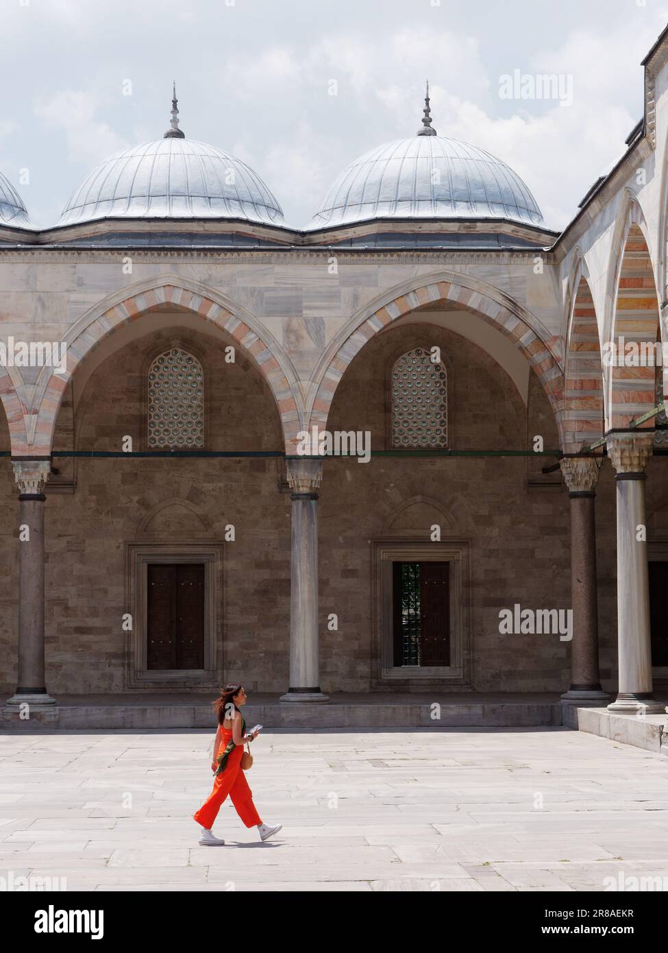 Lady in orange walking in the courtyard aka sahn of the Suleymaniye Mosque, Istanbul, Turkey Stock Photo