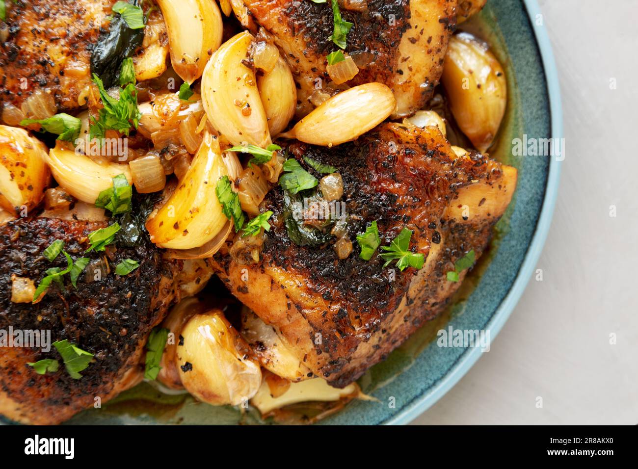 Homemade Chicken With 40 Cloves of Garlic on a Plate, top view. Close-up. Stock Photo