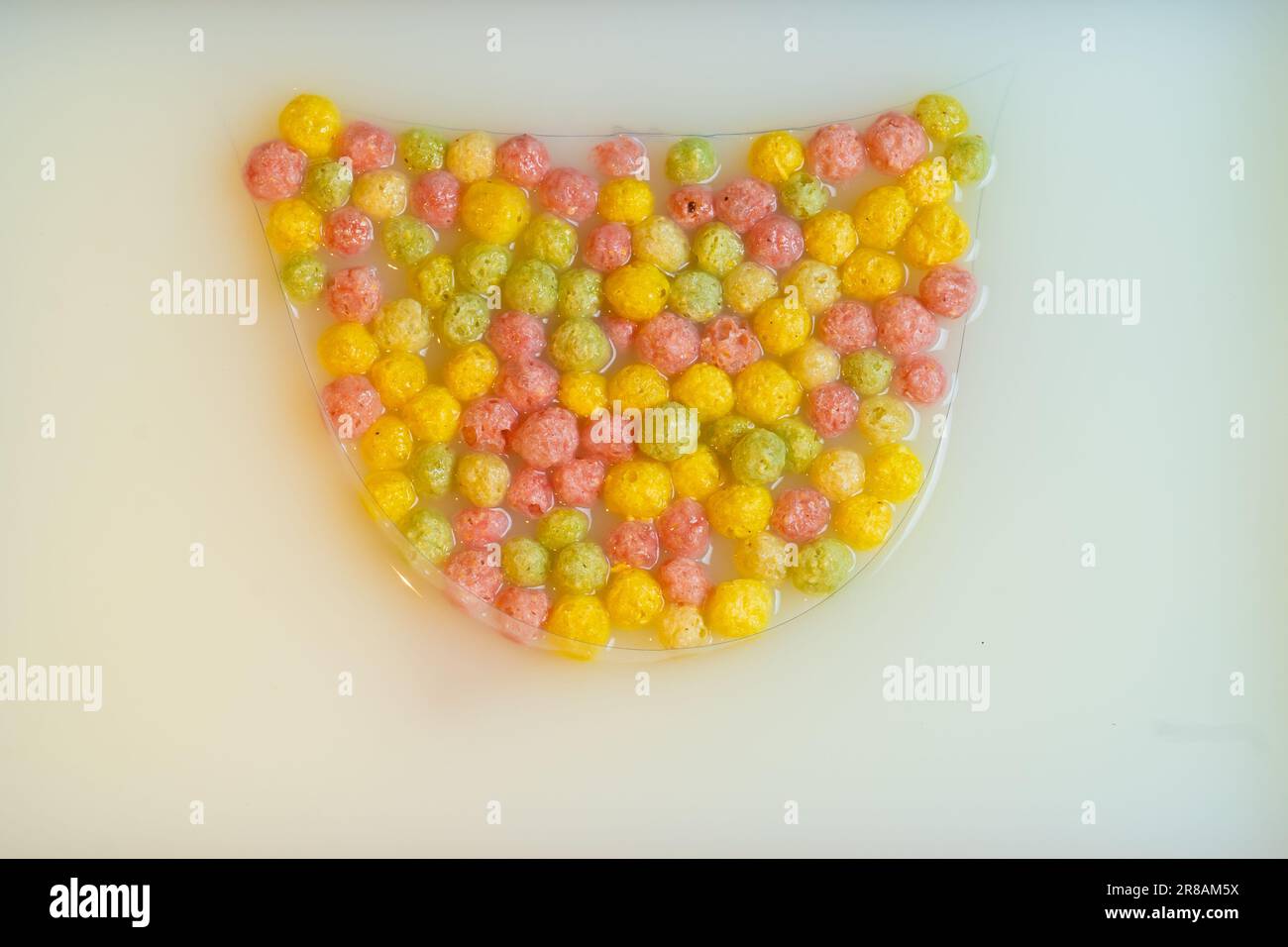 Top view on dry breakfast cereals, yellow, pink, green corn balls in