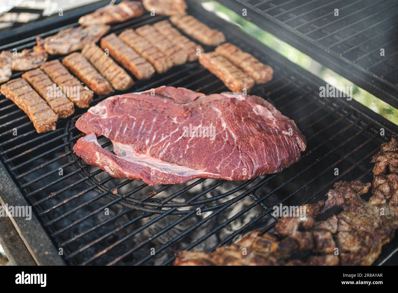 A close-up of an assortment of grilled meats cooking on a hot plate Stock Photo