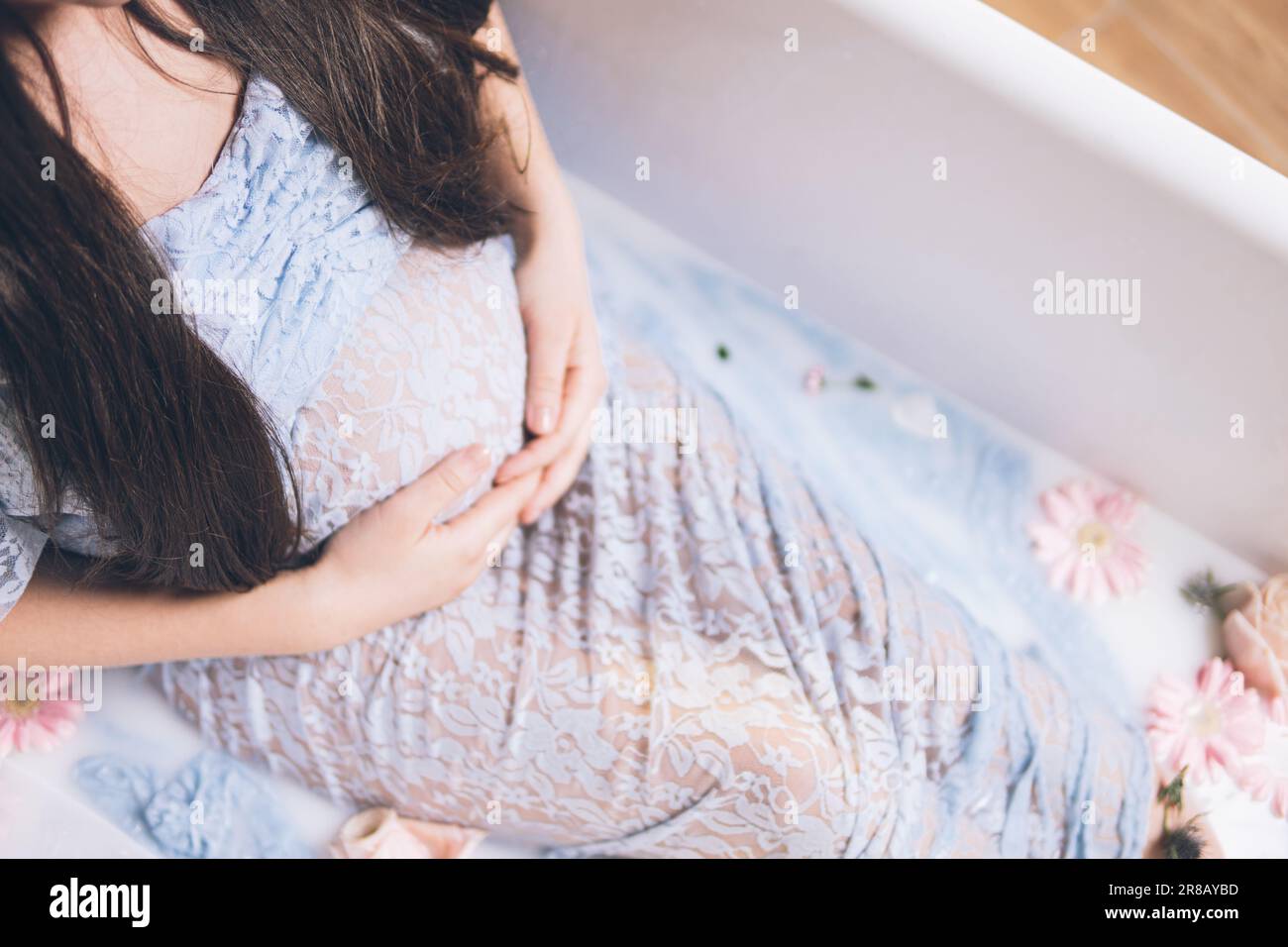A pregnant female relaxing in a bubble bath surrounded by a plethora of