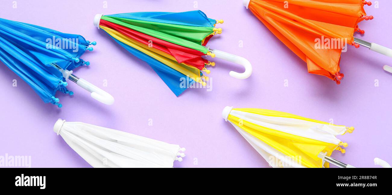 Many small umbrellas on lilac background Stock Photo