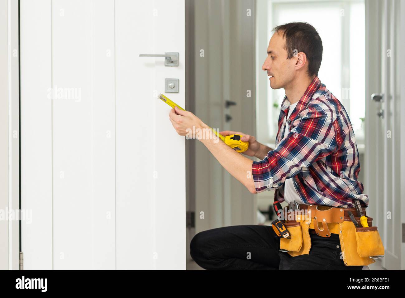 Master with screwdriver installs door hinges. Stock Photo