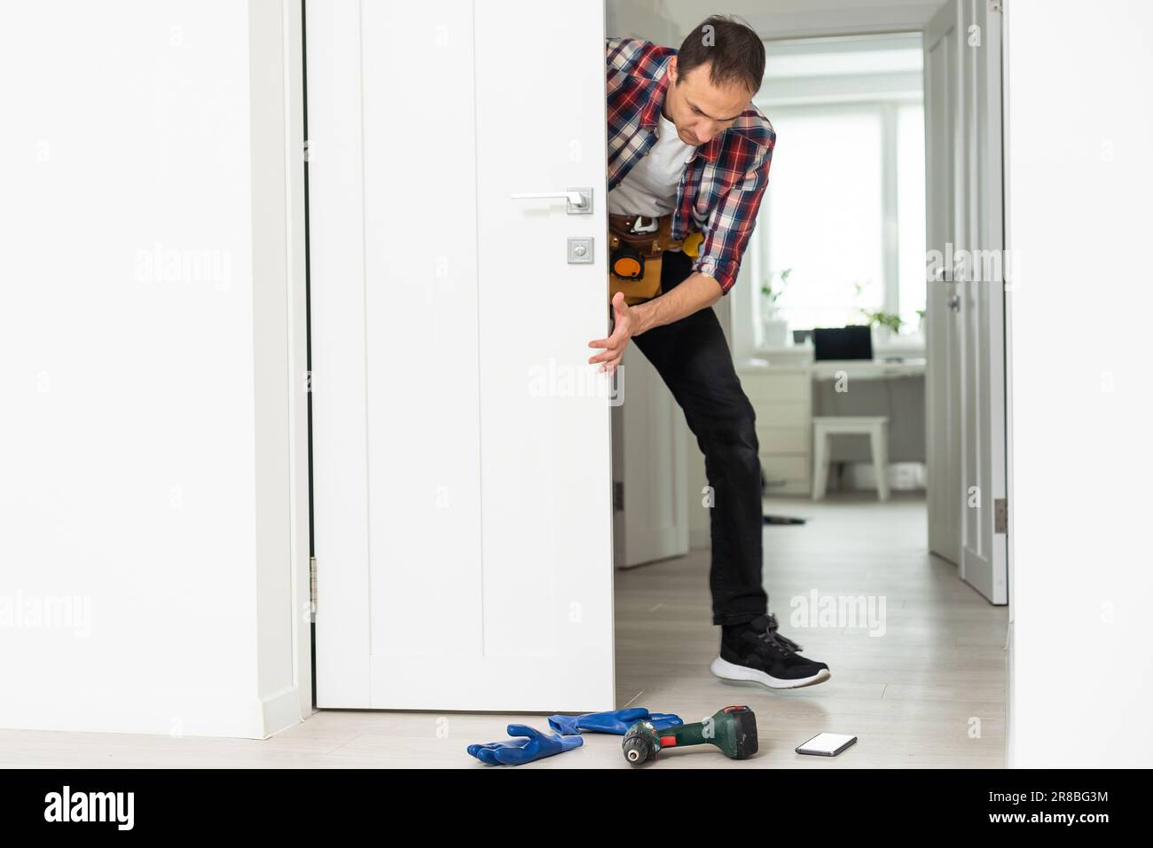 Master with screwdriver installs door hinges. Stock Photo