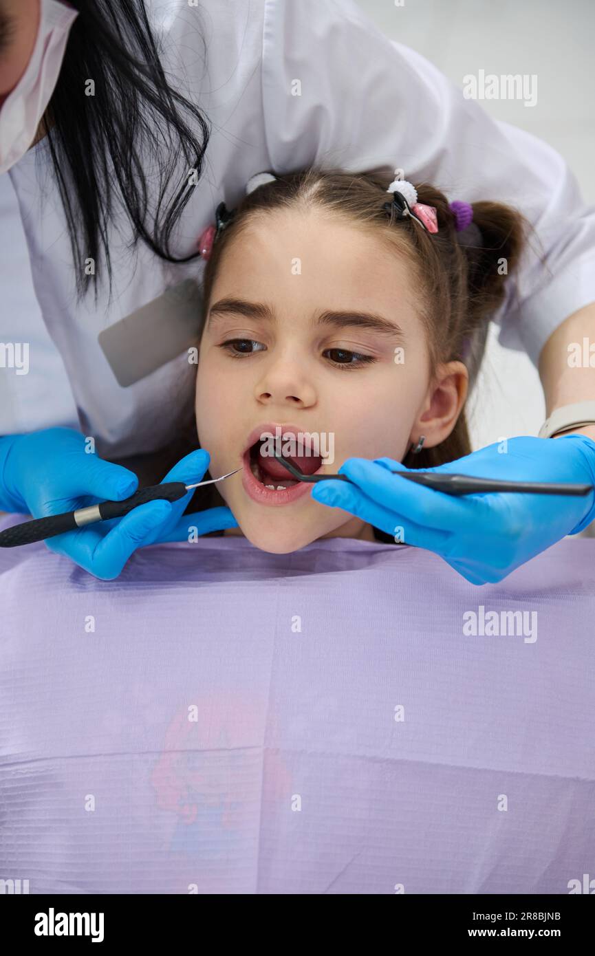 Close-up of little child girl in dentist's chair, being examined by a doctor dentist, curing caries in dentistry clinic Stock Photo