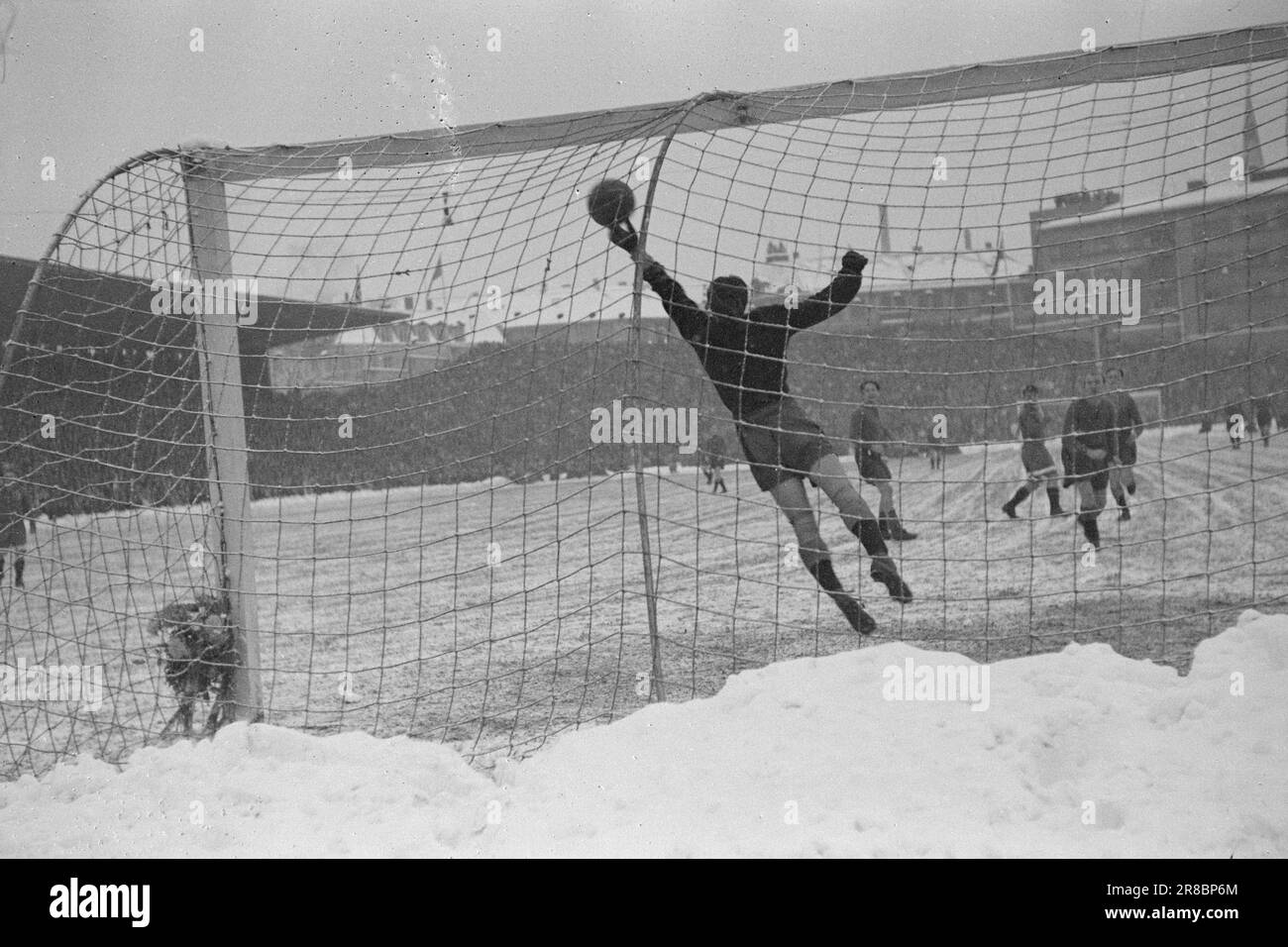 Current 23-3-1947: Dynamo Skeid in winter modeThe 'Dynamo'-'Skeid' match at Bislett was in every respect one of the strangest football matches on the Norwegian field. Before and during the match, it snowed heavily, and the grass was white and hard with snow drifts around when the players made their entrance and were hailed by 32,000 spectators - a record at Bislett. It was a display of good football.  Great save! It is 'Skeid's' goalkeeper in the second half, Knut Arnevaag, who catches a hard shot from 'Dynamo's' center forward, Sergei Solovjev.  Photo: Th. Skotaam / Aktuell / NTB ***PHOTO NOT Stock Photo