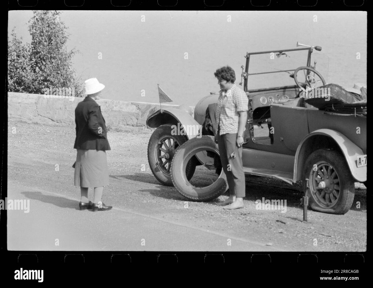 Current 32-7-1960: On the fly with old wheels.Can a young lady of today manage to master a capricious old car on hard mountain roads? Sverre A. Børretzen describes a daring journey Oslo - Årdal - Oslo with the Buick Ambrosius (41 years old) driven by Brit Hedberg (21 years old). Close to Fagernes with a punctured rear tyre. Will someone help help a punctured lady? Brit tried it with sad results. Photo: Sverre A. Børretzen / Aktuell ****PHOTO IS NOT IMAGE PROCESSED*** Stock Photo