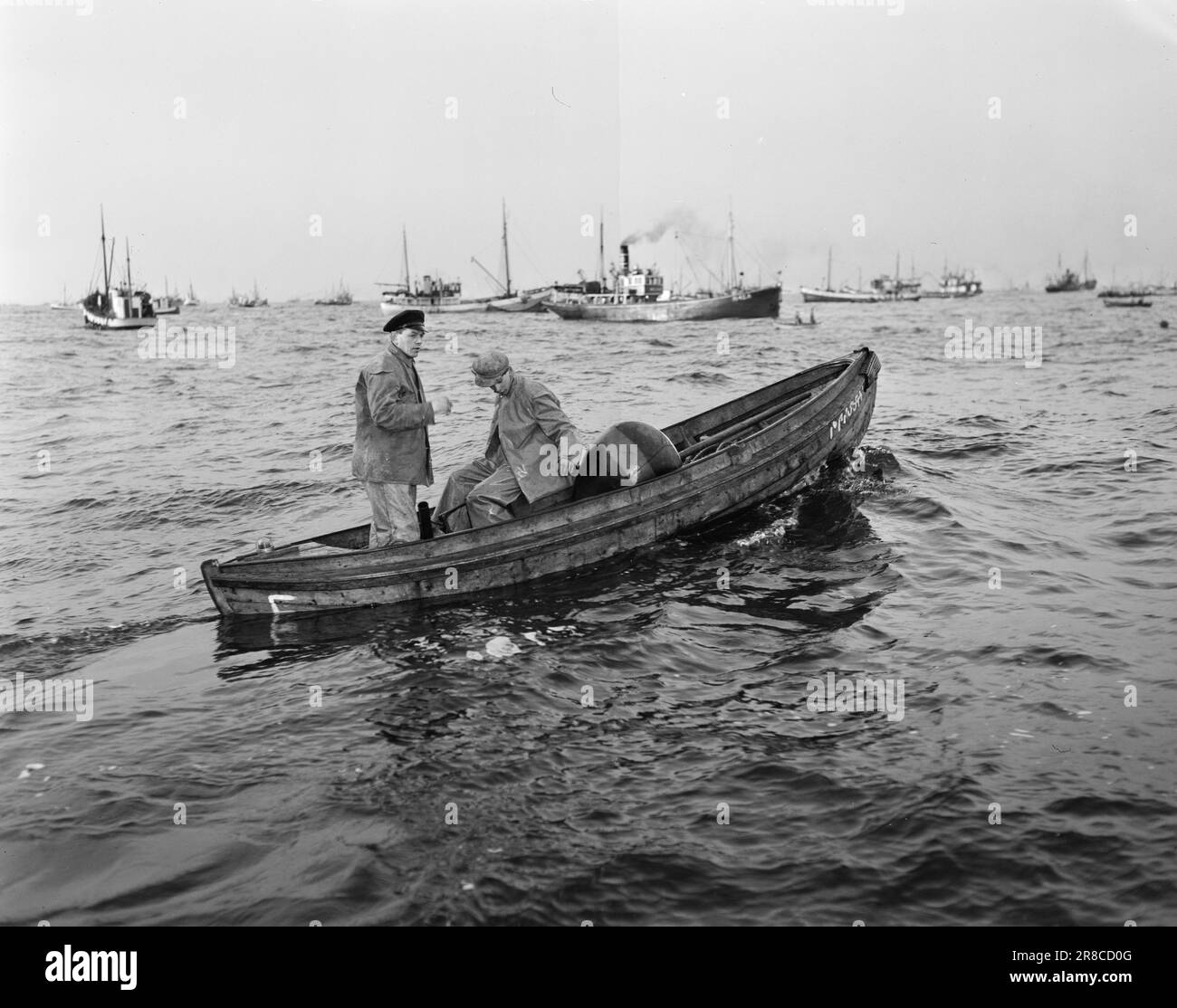 Aktuell 07-1950: The industrial city on Stadthavet.Aksel Sandemose and photographer Sverre A. Børretzen took part in this year's herring fishing, for 5 days they were aboard the spinner 'Fisk'.  The seine base in the light boat with a plumb line and a watchful expression on his face. With the help of the plumb line, he finds out everything about the herring.  Photo: Sverre A. Børettzen / Aktuell / NTB  ***PHOTO NOT IMAGE PROCESSED*** Stock Photo