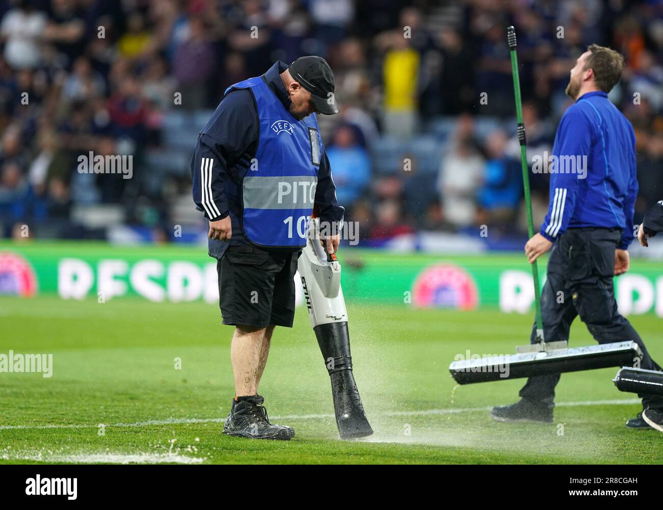 Ground staff clear water off the pitch while play is suspended during
