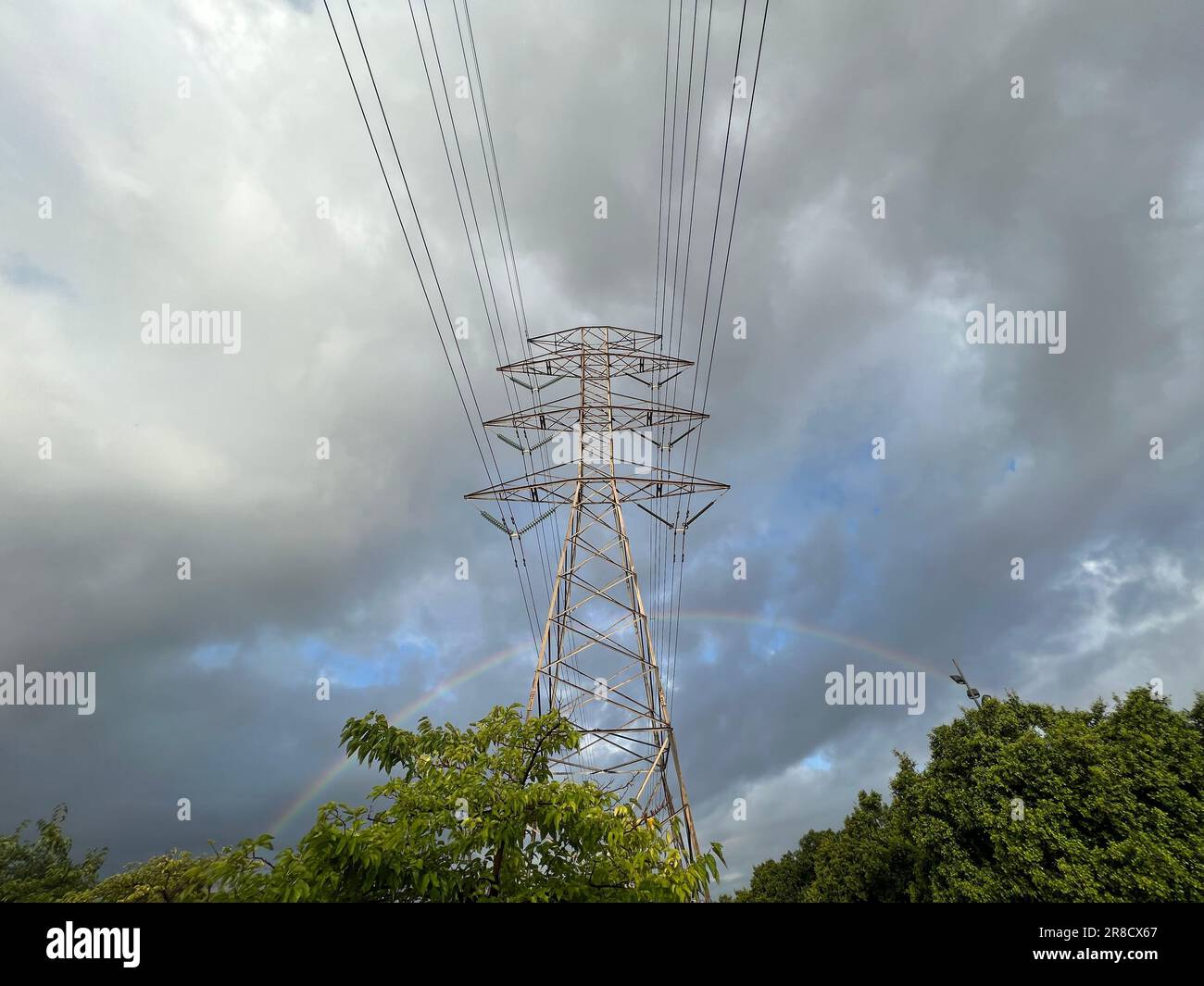 A scenic view of a cloudy sky with a thin rainbow arching under the ...