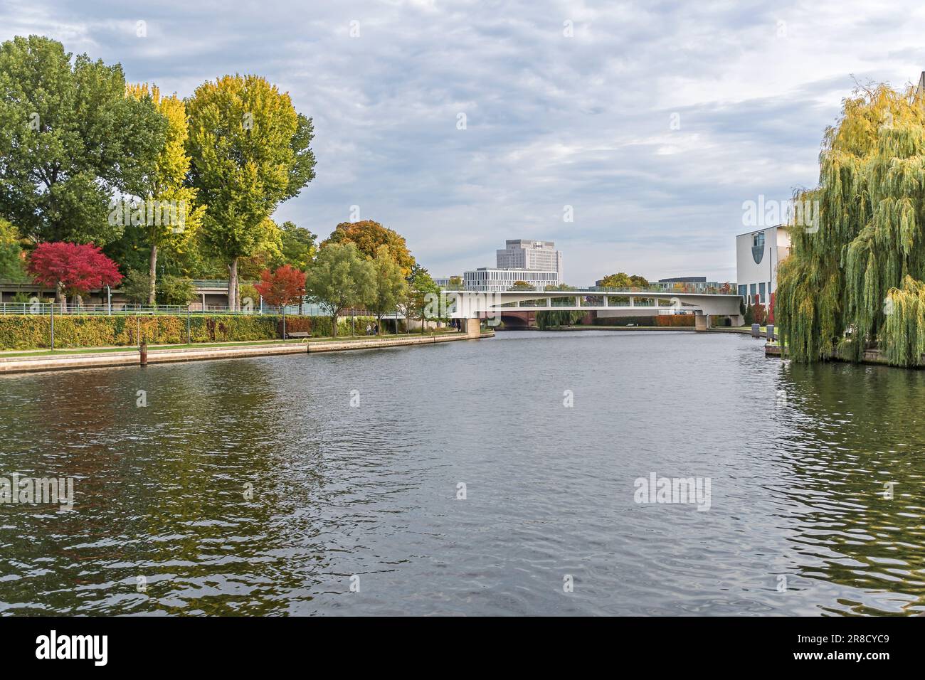 Berlin, Germany - October 5, 2022: River Spree lined with autumn coloured trees, the building of the Charite and the rear part of the German Federal C Stock Photo