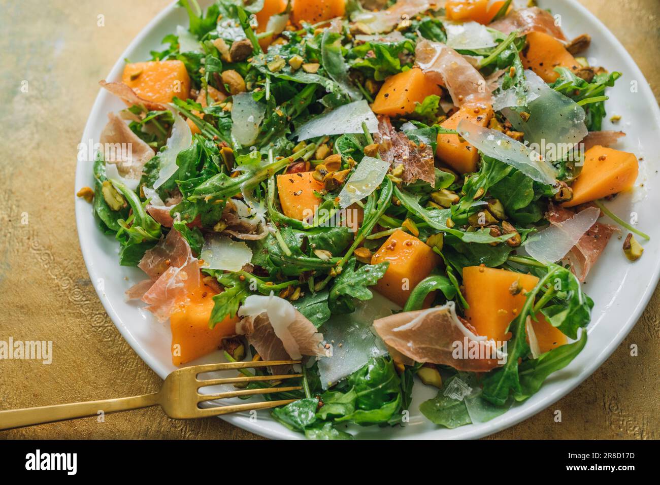 arugula salad with cheese, cantaloupe, prosciutto, pistachios on white