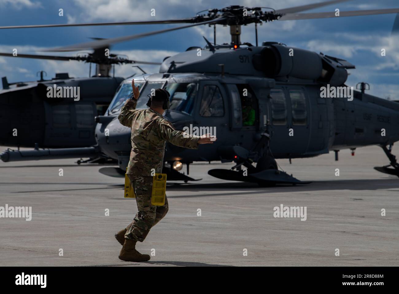 An Airman with the 33rd Helicopter Maintenance Unit marshals an HH-60 Pave Hawk to its parking space during Red Flag-Alaska 2023 at Eielson Air Force Base, Alaska, June 14, 2023. The Joint Pacific Alaska Range Complex is the largest instrumented air, ground and electronic combat training range in the world, given its expansive co-located air and land ranges and potential for co-located air and sea ranges. (U.S Air Force photo by Senior Airman Cedrique Oldaker) Stock Photo