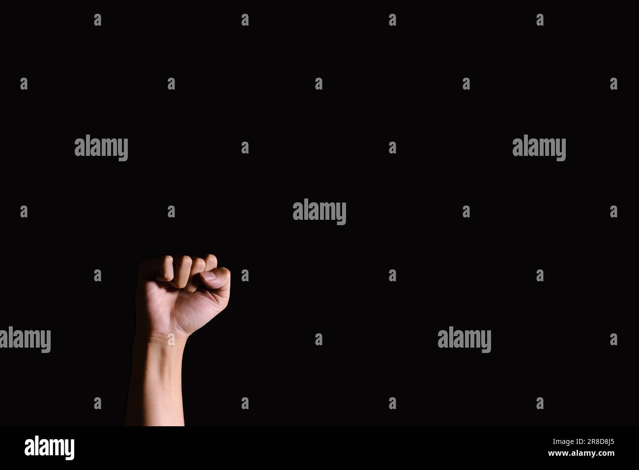 Low key shot of a hand fists up in the air. Isolated black background. Dramatic. Stock Photo
