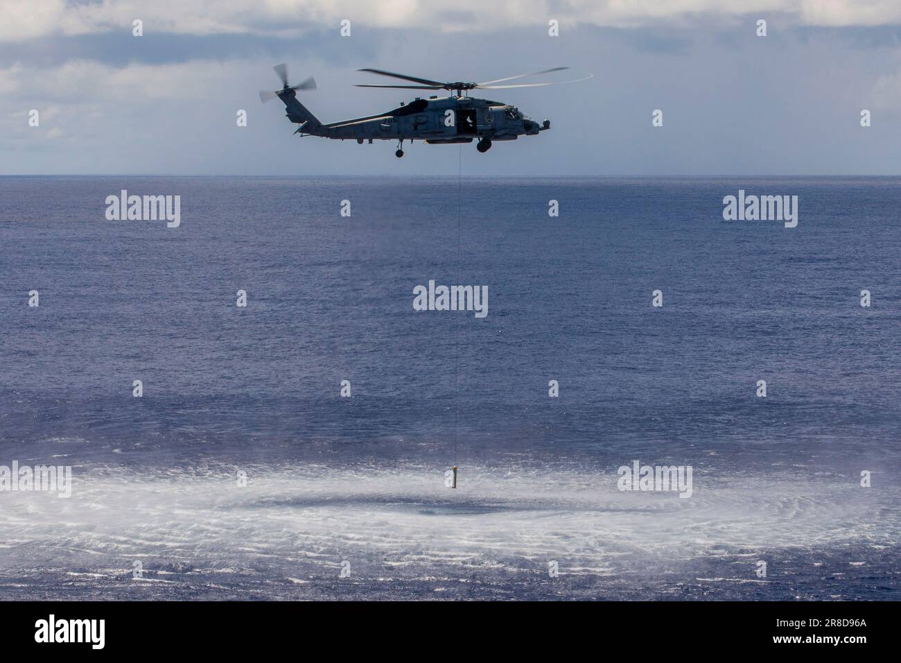 230618-N-PA221-1230 PACIFIC OCEAN (June 18, 2023) An MH-60R Sea Hawk helicopter from the 'Battlecats' of Helicopter Maritime Strike Squadron (HSM) 73 lowers an airborne low-frequency sonar (ALFS) into the water near the aircraft carrier USS Nimitz (CVN 68). Nimitz is underway conducting routine operations. (U.S. Navy photo by Mass Communication Specialist 3rd Class Kevin Tang) Stock Photo