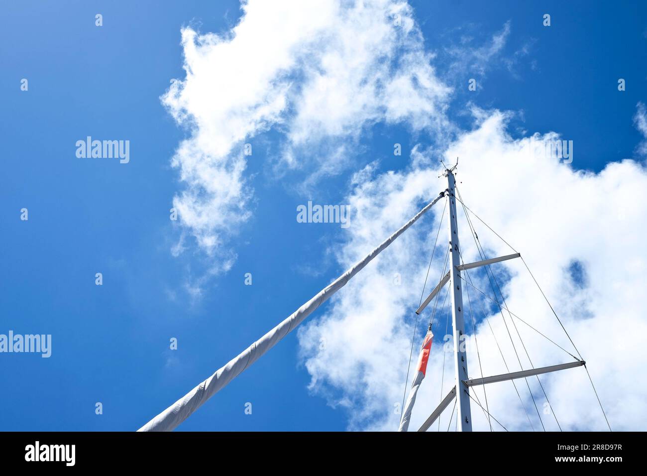 a mast of a sailboat with blue sky and white clouds Stock Photo