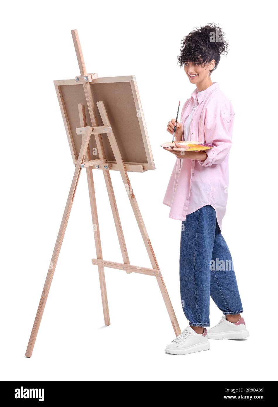 Young woman painting on easel with canvas against white background ...