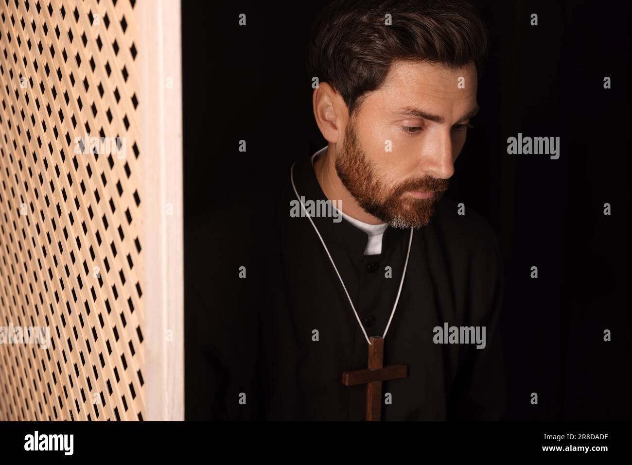 Catholic priest wearing cassock in confessional booth Stock Photo - Alamy