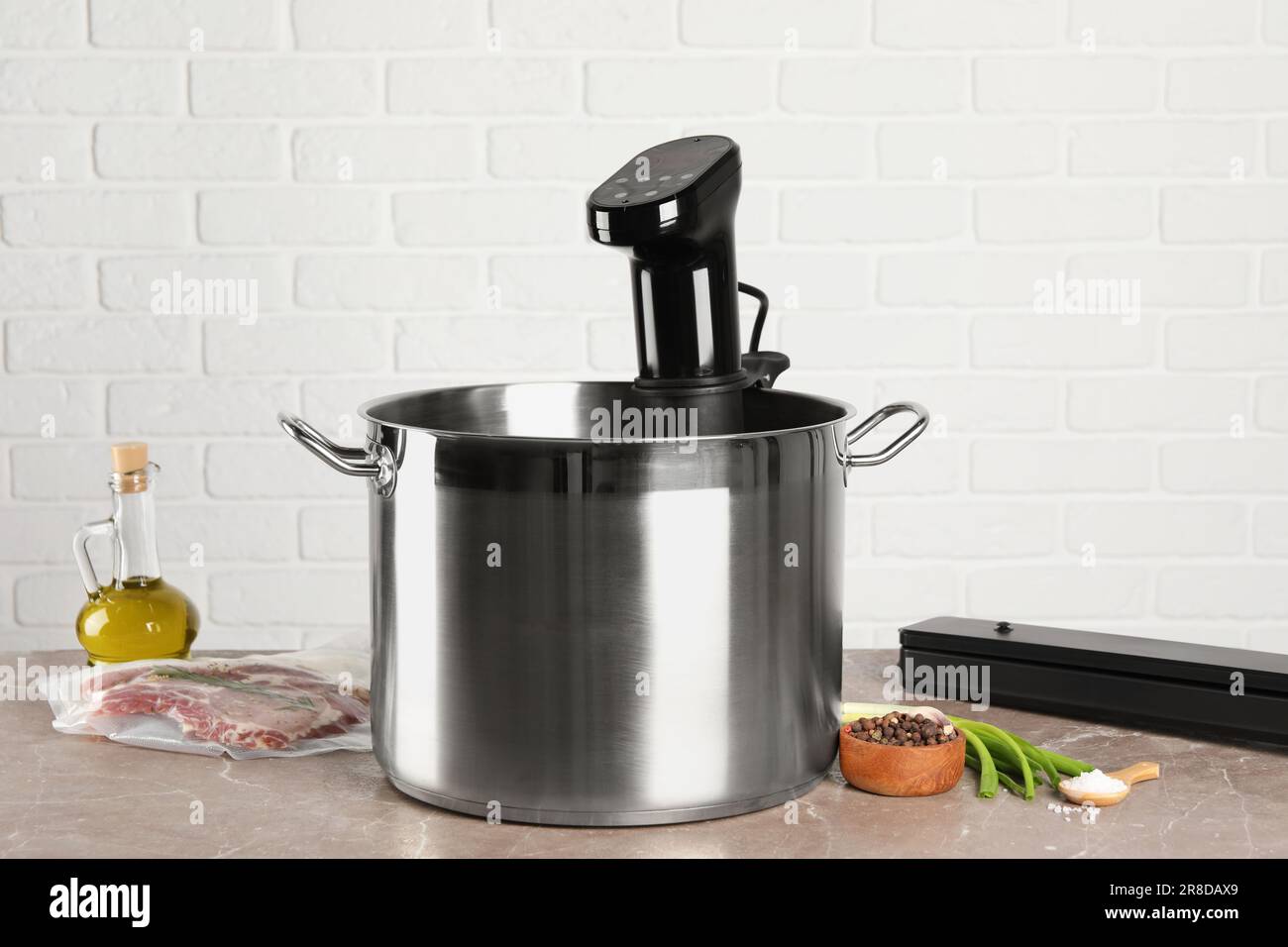 Thermal immersion circulator in pot and ingredients on grey marble table. Sous vide cooking