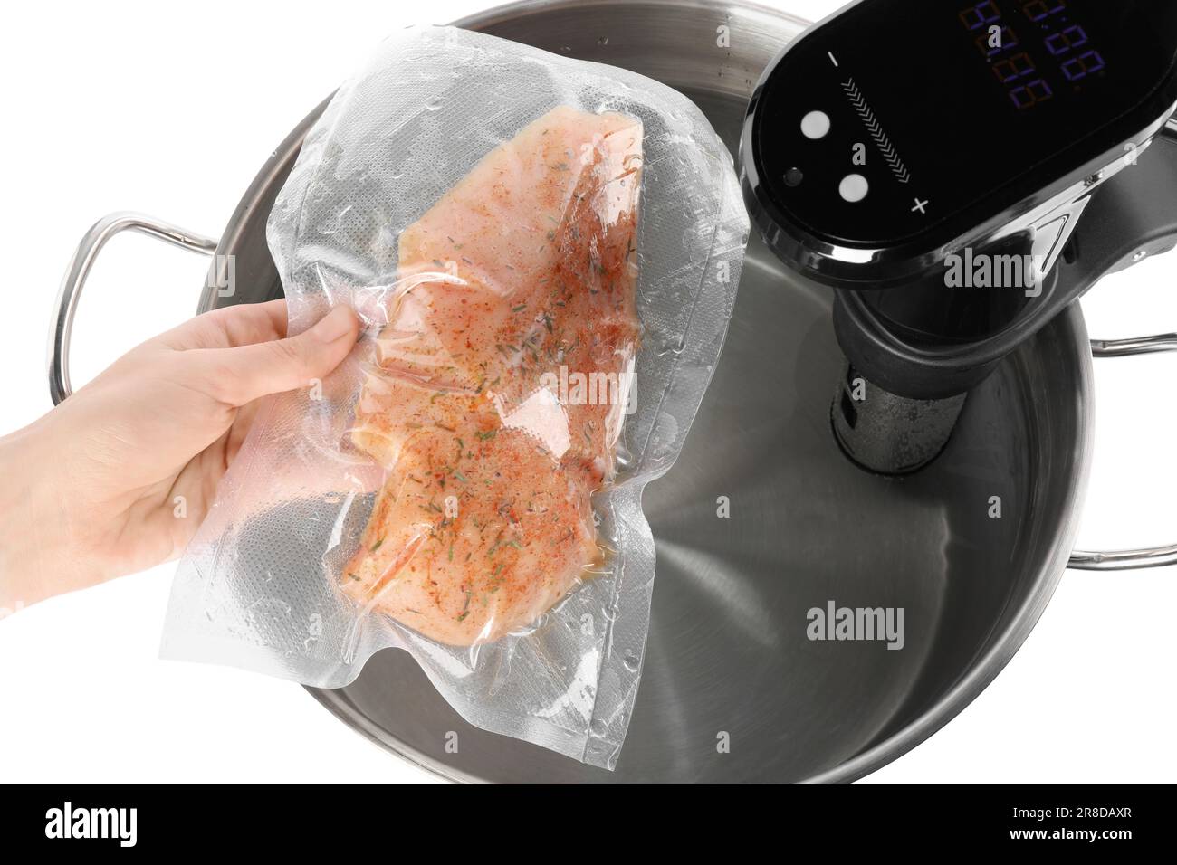 Woman putting vacuum packed meat into pot with sous vide cooker on