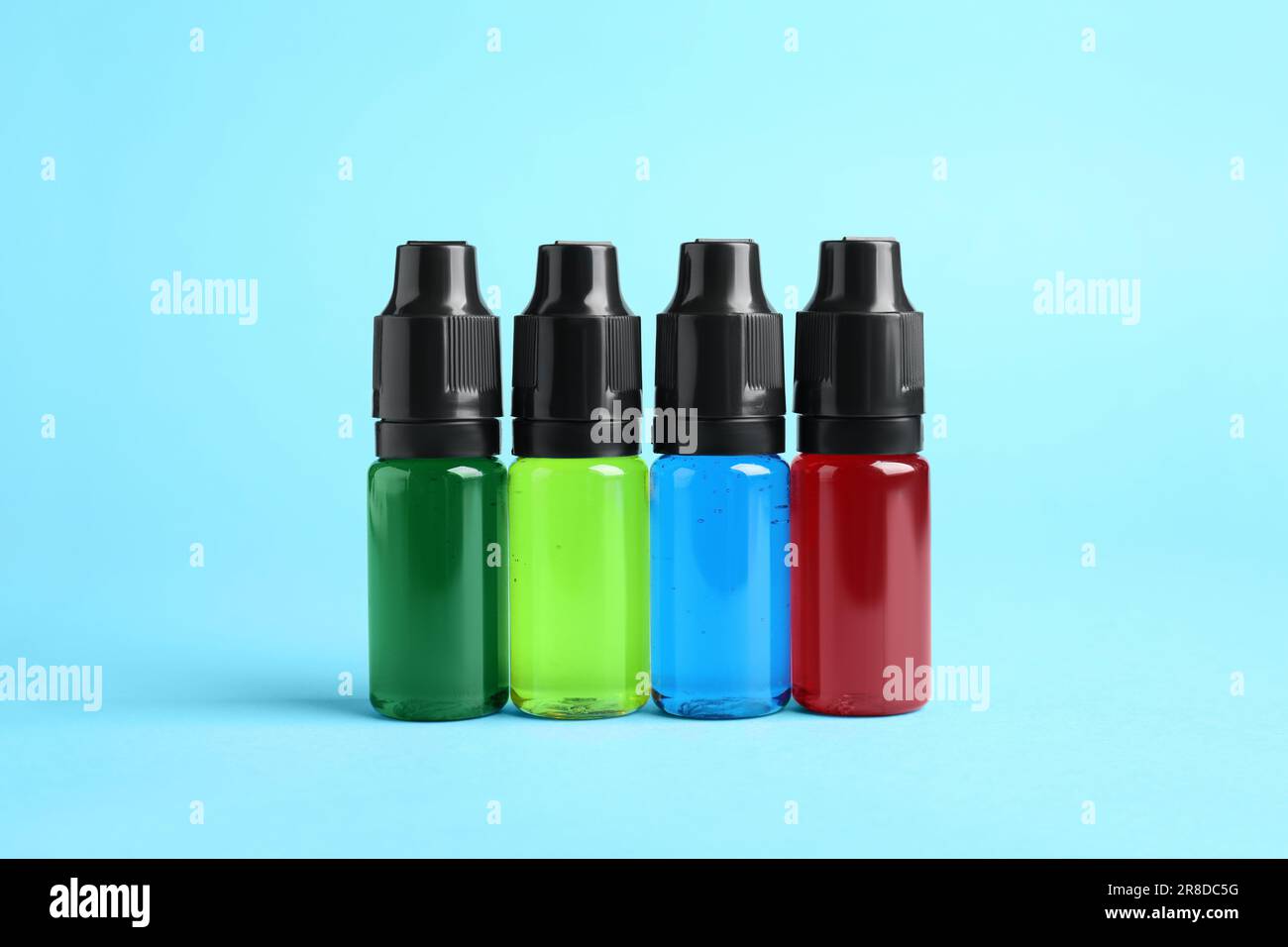 Bottles with different food coloring on light blue background Stock Photo