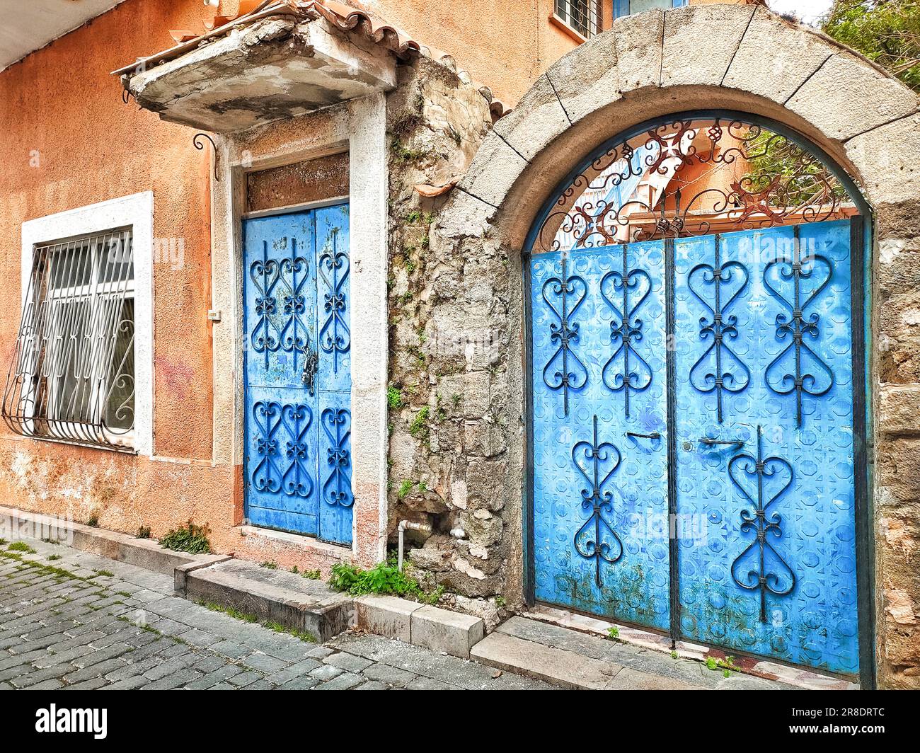 Facade of old village house with blue door and gate, with patterned ...