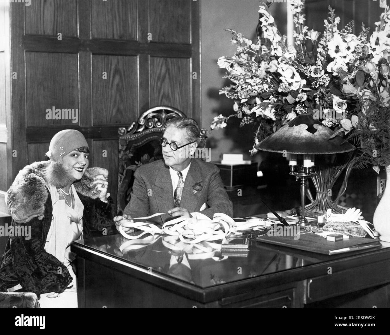 New York, New York:   c. 1929 Stage star Irene Bordini visits the new uptown Hutton & Co stock brokerage office. She was the first customer at the new office and is looking over the tape with W.D. Hutton. Stock Photo