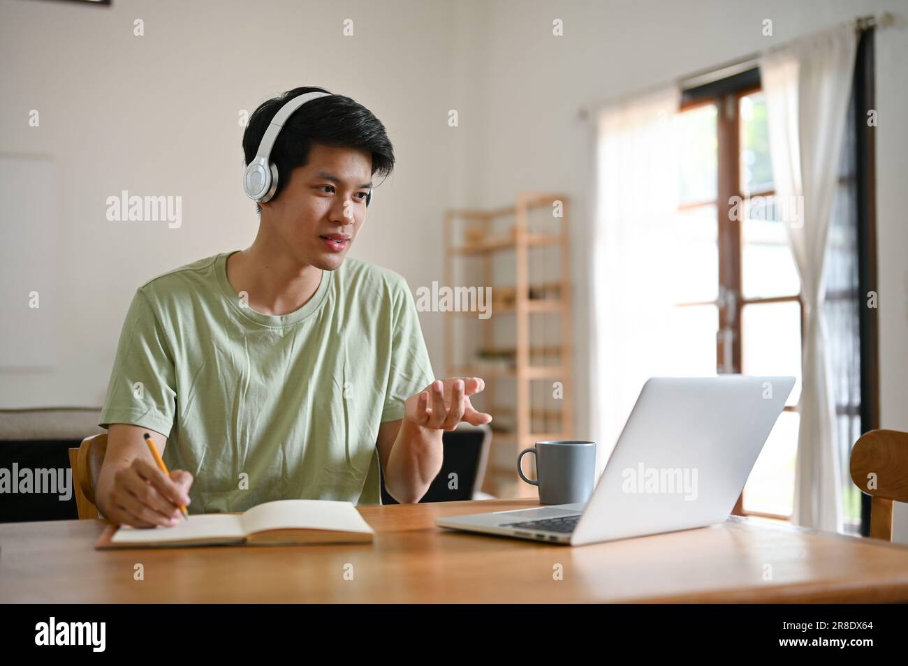 A smart and handsome young Asian male college student wears headphones ...
