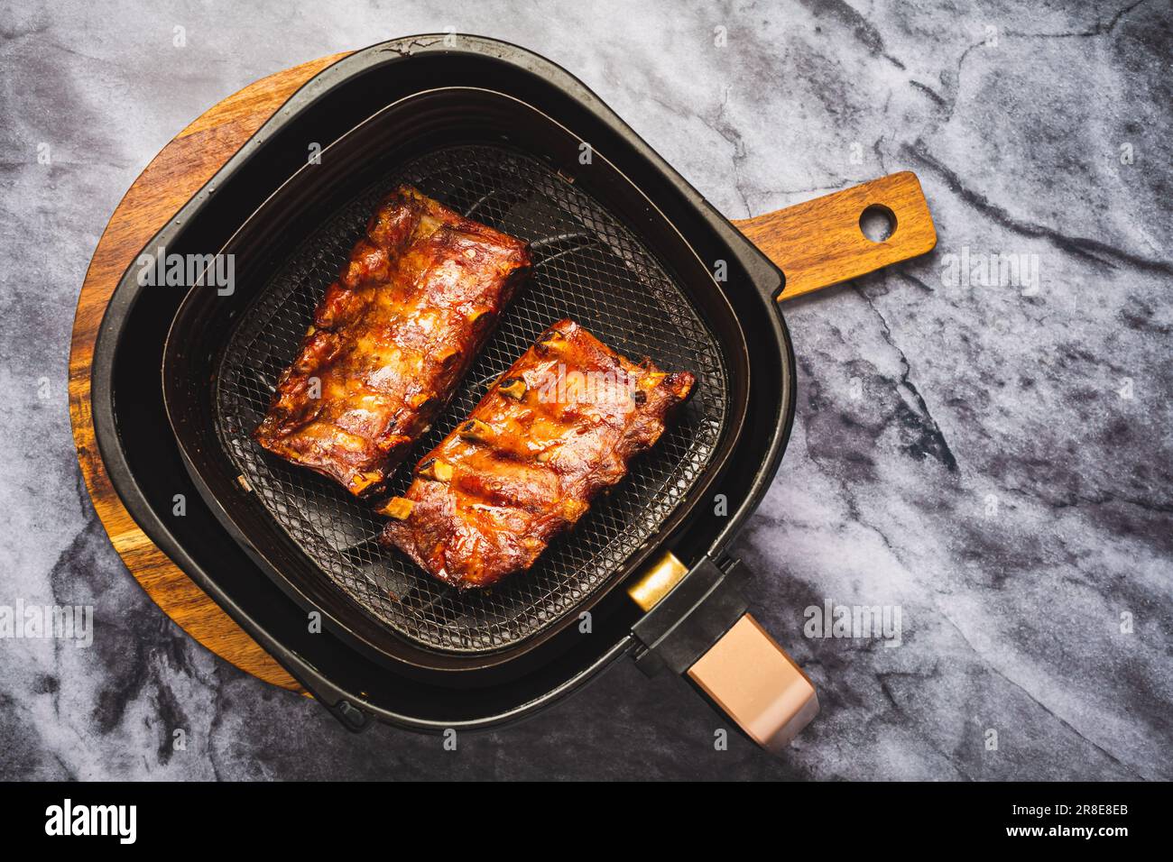 Modern cooking preparing juicy spare ribs with honey sauce in airfryer, BBQ meat Stock Photo