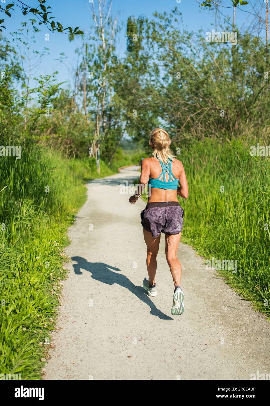 Senior athletic fit woman running in the summer park. Elderly woman jogging outdoor. Mature woman exercising. Healthy active life concept. Copyspace f Stock Photo