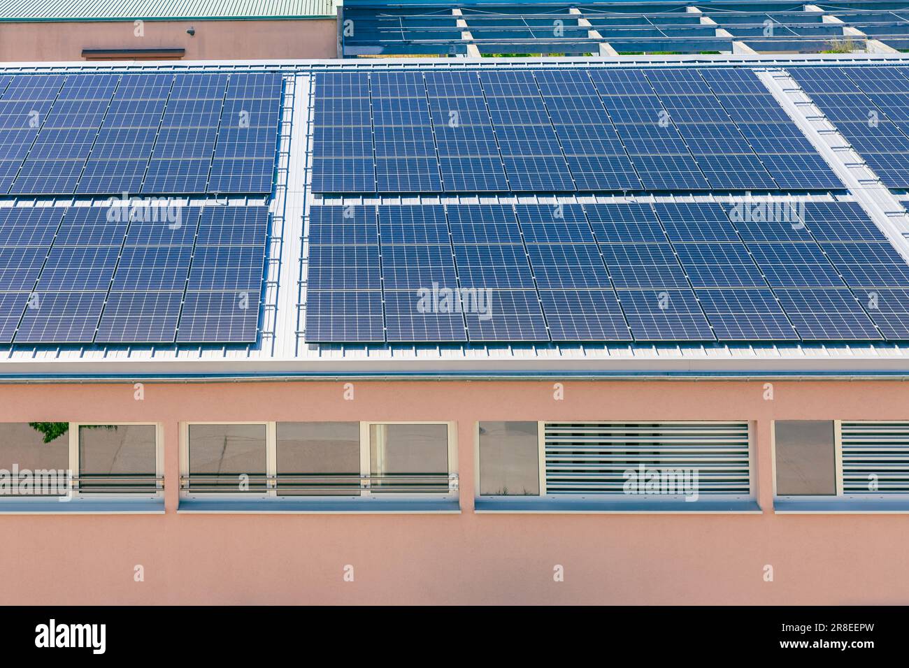 Solar panels installed on a roof of a large industrial building or a warehouse. Stock Photo