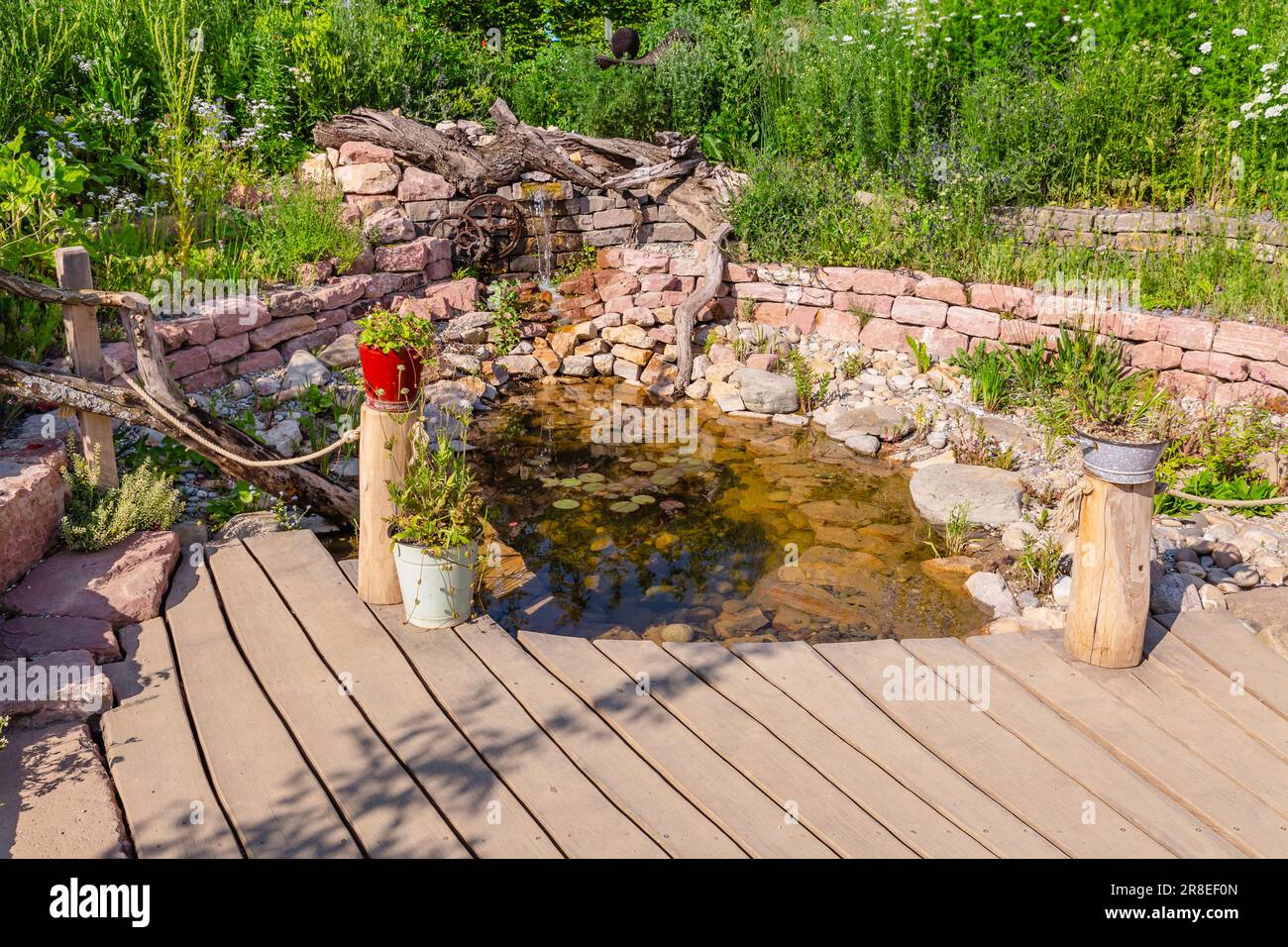 Natural garden with small patio, native plants, natural stones, pond and potted plants Stock