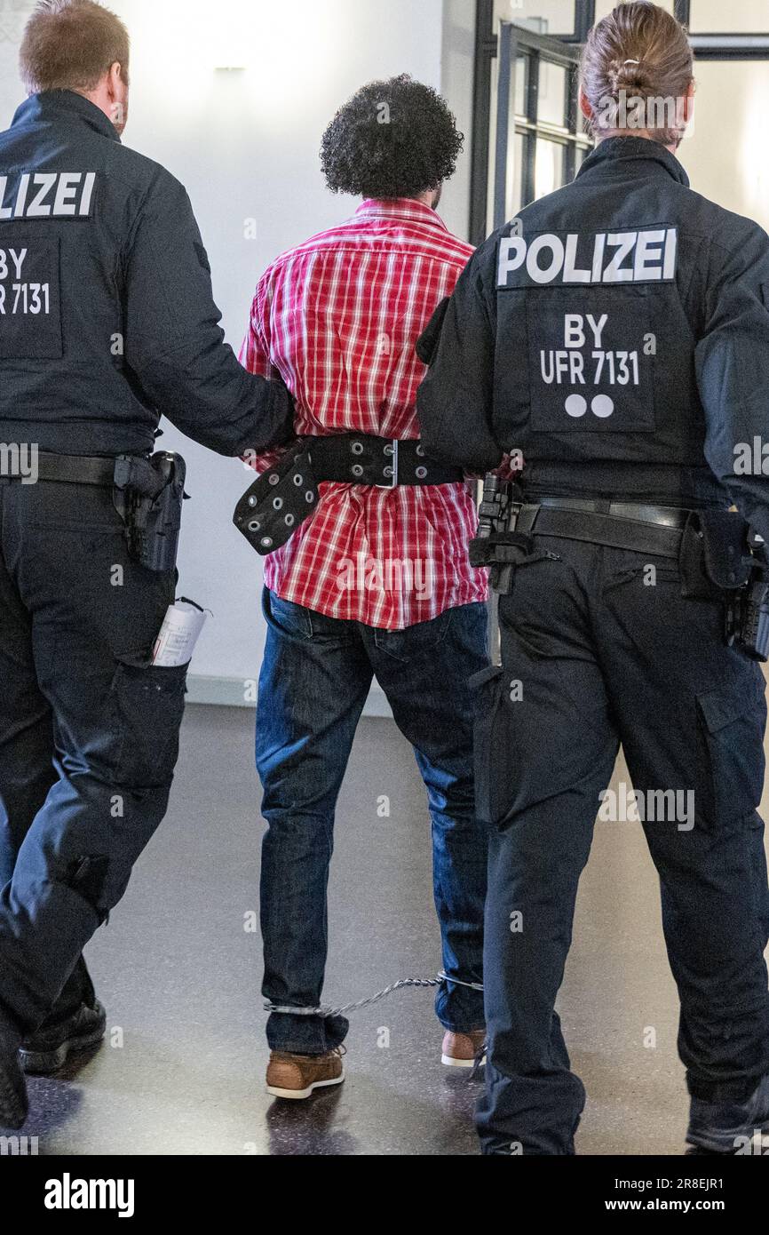 Regensburg, Germany. 21st June, 2023. The defendant is led to the courtroom in shackles by police officers because of an appeal. With a jump out of the window of the Regensburg District Court, the man sentenced to life imprisonment for the murder of a 76-year-old woman in Nuremberg in 2011 had caused an international police operation in January. Credit: Armin Weigel/dpa/Alamy Live News Stock Photo